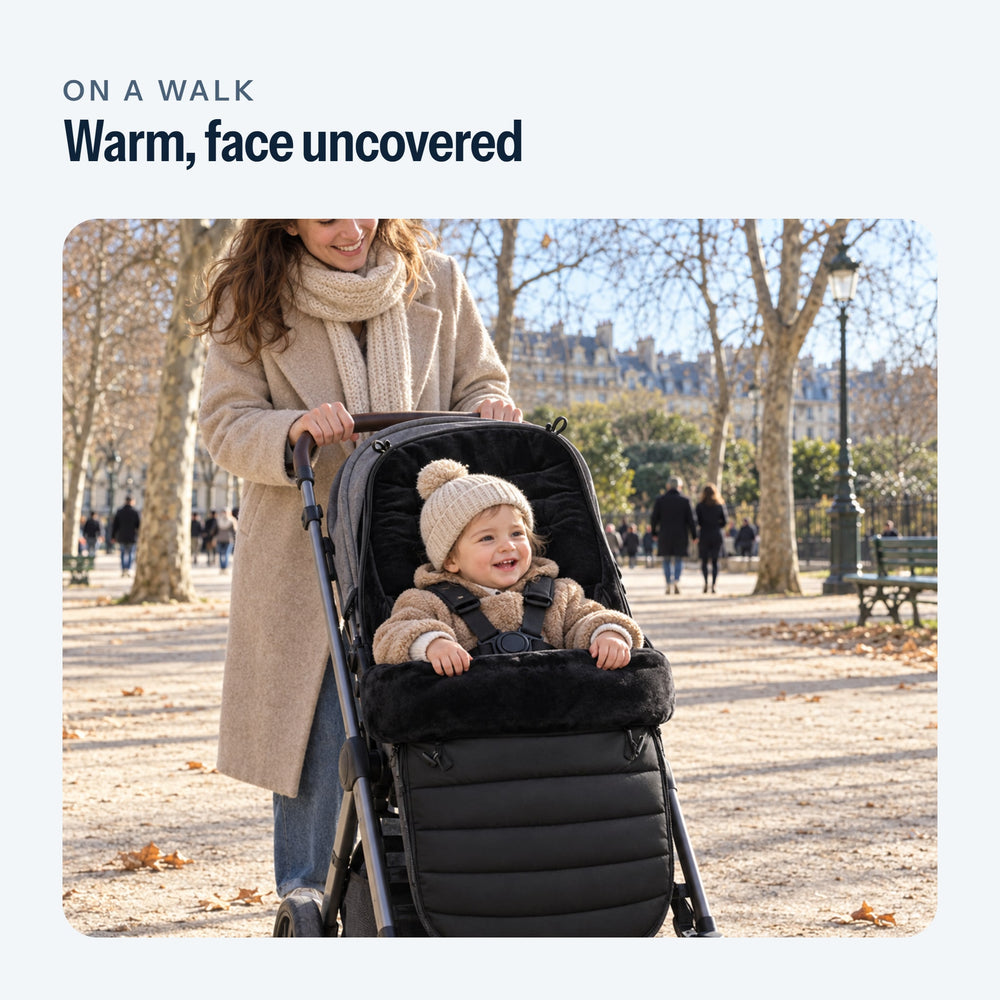 Parent on a walk, baby in the black footmuff, face uncovered