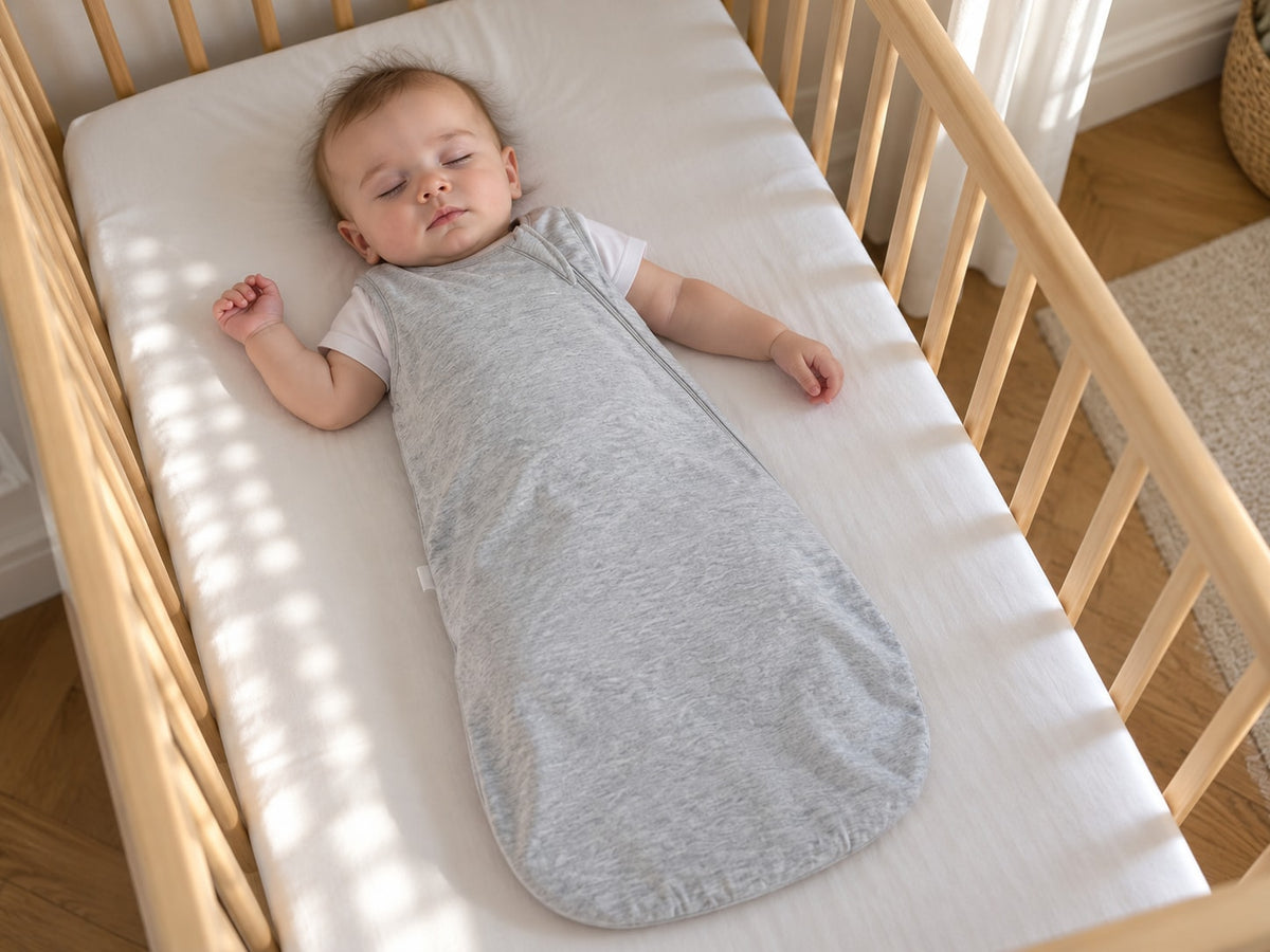 Baby asleep on their back in an empty crib, covered by the Securidou sleep sack