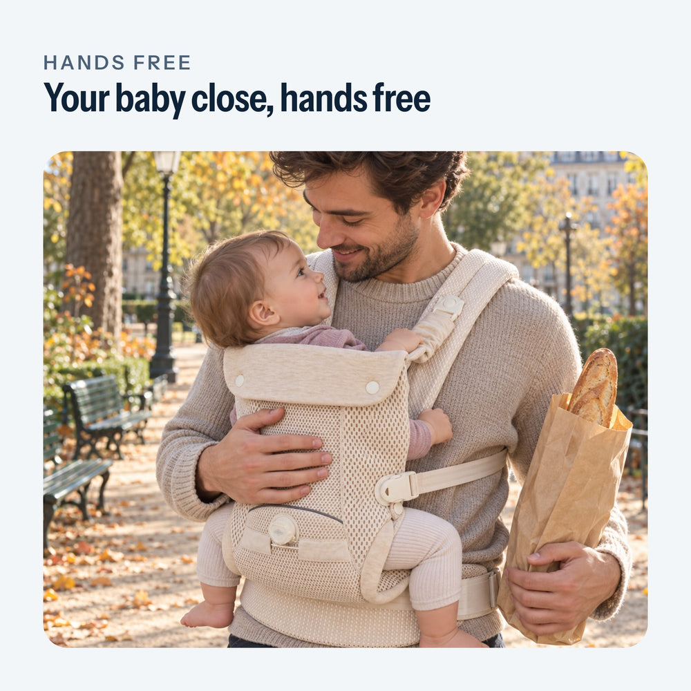 Father on a walk, his baby facing him in the beige baby carrier, one hand on the baby’s back